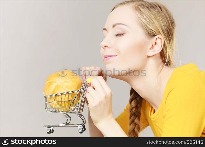 Buying gluten food products concept. Woman holding shopping cart trolley with small piece of bread bun. Woman holding shopping cart with bread
