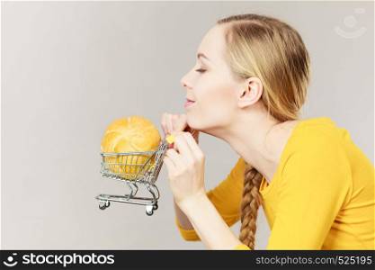 Buying gluten food products concept. Woman holding shopping cart trolley with small piece of bread bun. Woman holding shopping cart with bread