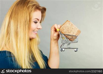 Buying gluten food products concept. Woman holding shopping cart trolley with small piece of bread. Woman holding shopping cart with bread
