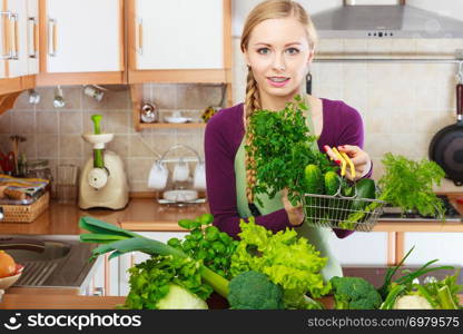 Buying healthy dieting food concept. Woman in kitchen having many green vegetables holding small shopping basket trolley.. Woman in kitchen having vegetables holding shopping basket