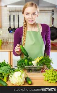 Buying healthy dieting food concept. Woman in kitchen having many green vegetables holding small shopping basket trolley.. Woman in kitchen having vegetables holding shopping basket