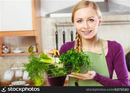 Buying healthy dieting food concept. Woman in kitchen having many green vegetables holding small shopping basket.. Woman in kitchen having vegetables holding shopping basket