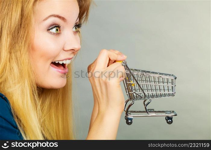 Buying things at market shops concept. Happy smiling woman hand holding small tiny shopping cart trolley. Happy woman holding small tiny shopping cart