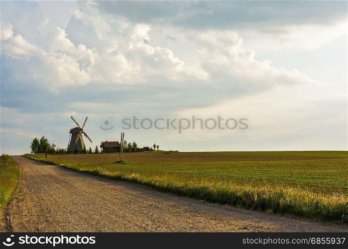 By located among fields of lonely windmill and farmhouse laid dirt road