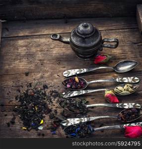 by spilling tea spoons. varieties of dry tea infuser scattered on wooden table