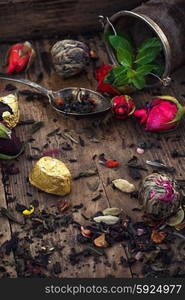 by spilling tea spoons. varieties of dry tea infuser scattered on wooden table