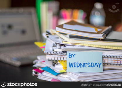 By Wednesday; Stack of Documents and Laptop at working Desk.