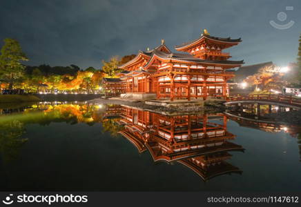 Byodoin Temple Pagoda and lake with red maple leaves or fall foliage in autumn season. Colorful trees, Kyoto, Japan. Nature and architecture landscape background.