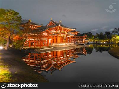 Byodoin Temple Pagoda and lake with red maple leaves or fall foliage in autumn season. Colorful trees, Kyoto, Japan. Nature and architecture landscape background.