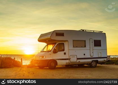 C&ing on nature beach. Caravan recreational vehicle at sunrise on mediterranean coast in Spain. Vacation and travelling in motorhome.. C&er car on beach at sunrise