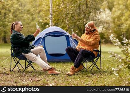 c&ing, tourism and travel concept - happy couple drinking beer and eating sandwiches at tent c&. couple drinking beer with sandwiches at tent c&
