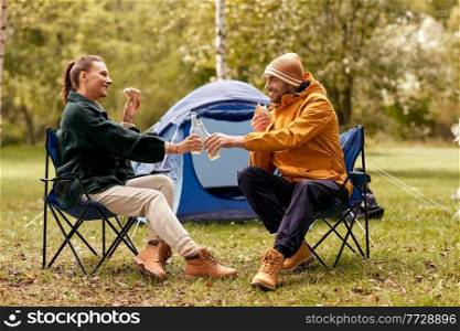 c&ing, tourism and travel concept - happy couple drinking beer and eating sandwiches at tent c&. couple drinking beer with sandwiches at tent c&