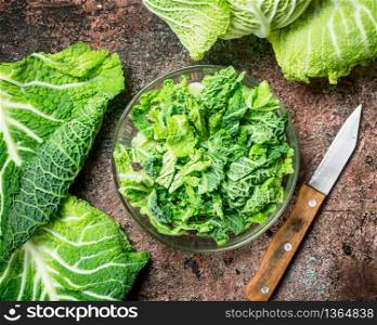 Cabbage salad in a bowl with a knife. On rustic background.. Cabbage salad in a bowl with a knife.