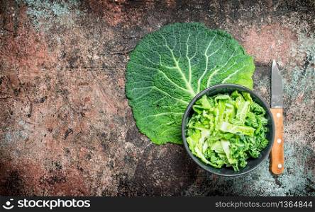 Cabbage salad in a bowl with a knife. On rustic background.. Cabbage salad in a bowl with a knife.