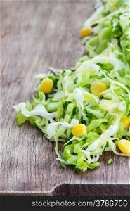 Cabbage salad with corn on wooden board, selective focus