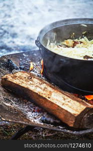 Cabbage with meat cooking in a cauldron on open fire during a festival in winter.