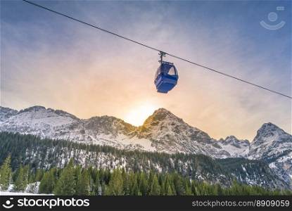 Cable car route over the Alps mountains - Cable car route going over the Austrian alps mountains with their fir forests, while the sun sets down behind the peaks. Image taken in Ehrwald, Austria.