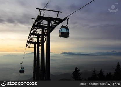 Cablecar transports skiers to the top of the mountain and the sun goes down