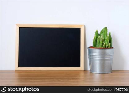 Cactus and blank vintage chalkboard on wooden table and white background, succulent desert houseplant trendy design background concept