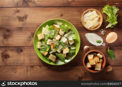 caesar salad and ingredients at wooden background