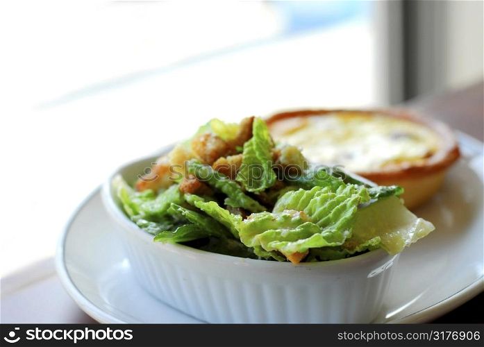 Caesar salad and quiche on white plate