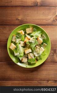 caesar salad in plate at wooden background