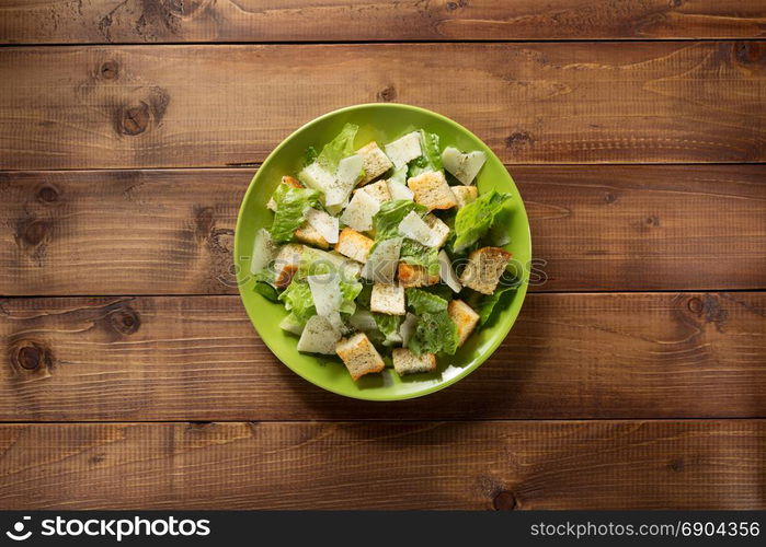 caesar salad in plate at wooden background