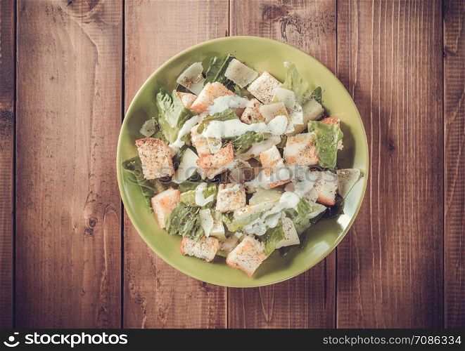 caesar salad in plate at wooden background
