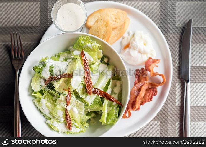 Caesar salad served with crispy bacon and poach egg