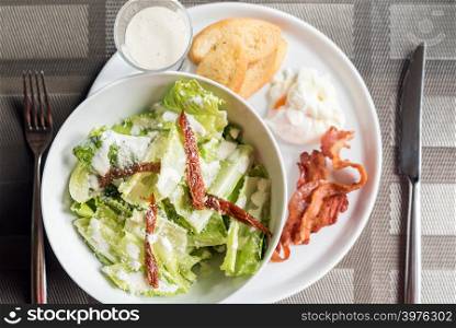 Caesar salad served with crispy bacon and poach egg