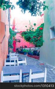 Cafe and restaurants at amazing narrow streets of popular destination on Crete island. Greece. Traditional architecture and colors of mediterranean city. Place for romantic vacation and summer travel