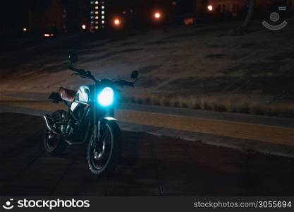Cafe racer scrambler motorcycle, old fashioned vehicle with modern materials on forest background