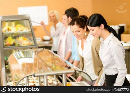 Cafeteria lunch two office colleagues woman choose food dessert self-service