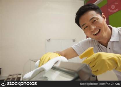 Cafeteria worker cleaning food serving area