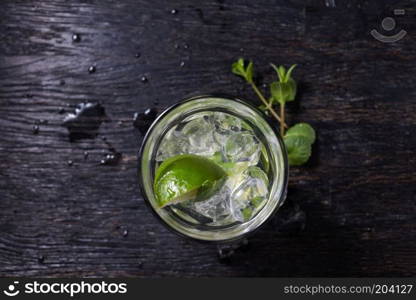 Caipirinha top view, Mojito cocktail from top, vodka or soda drink with lime mint isolated on black wooden background. Mojito cocktail from top, vodka or soda drink with lime mint isolated on black wooden background