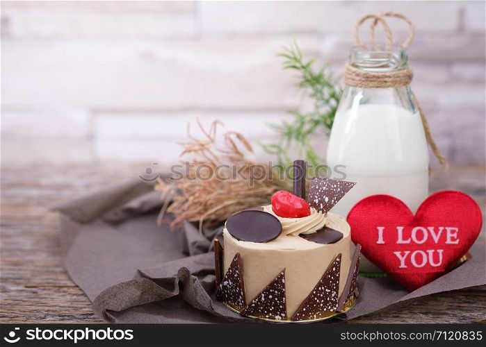 Cake and a bottle of milk on a wooden table in warm light, Vintage tone, Space to write, Valentine concept.