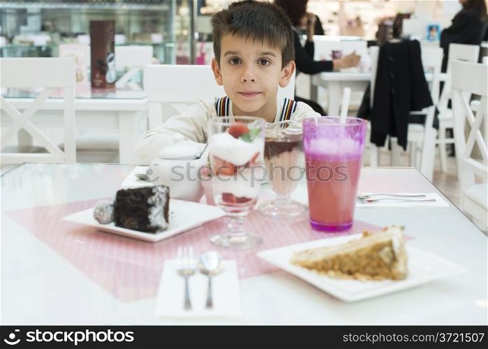 Cake and a milkshake in confectionery. Child on a table