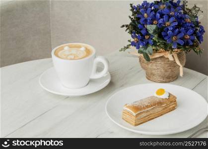 cake and cup of coffee on a table with flowers. cake in a plate and a cup on the table