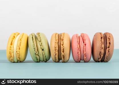 Cake macaron or macaroon on turquoise background from above, colorful almond cookies, pastel colors, vintage card, top view