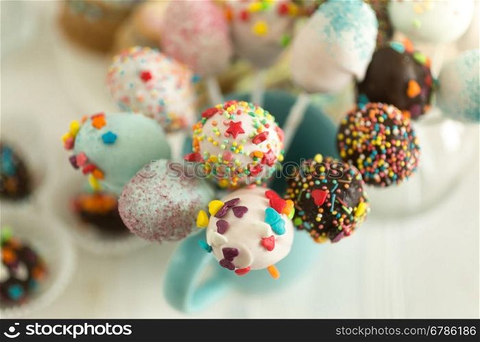 Cake pops decorated by colorful sprinkles on white background