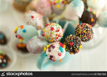 Cake pops decorated by colorful sprinkles on white background