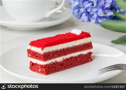 cake with a fork on a saucer and a flower on the table closeup. cake in a plate and a cup on the table
