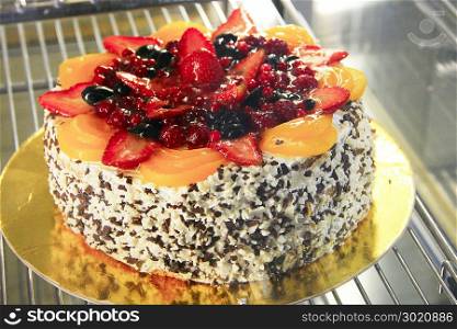 Cake with many berries on shopwindow. Cake with many berries raspberry apricot currants strawberry on shopwindow. Tasty cake