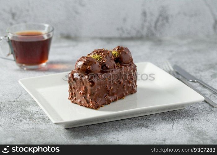 Cake with profiteroles with tea on stone table