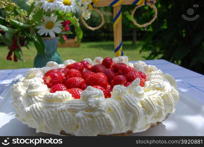 Cake with strawberries and cream at a summer decorated table in a garden