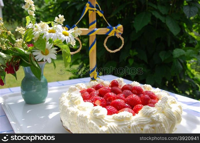 Cake with strawberries and cream at a summer decorated table in a garden