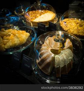 Cakes under bell-glass on display. bakery glass case full of different pieces of cakes