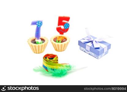 cakes with seventy five years birthday candles, whistle and gift on white
