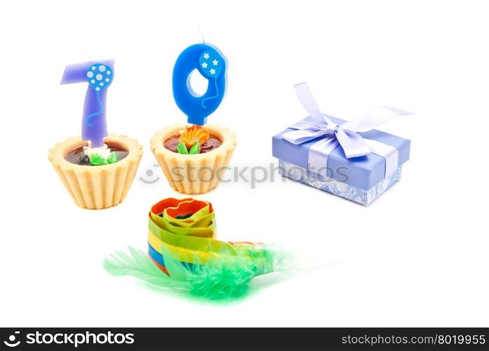 cakes with seventy years birthday candles, whistle and gift on white