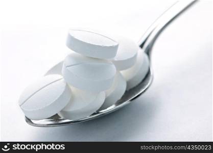 Calcium supplement pills piled on metal spoon closeup